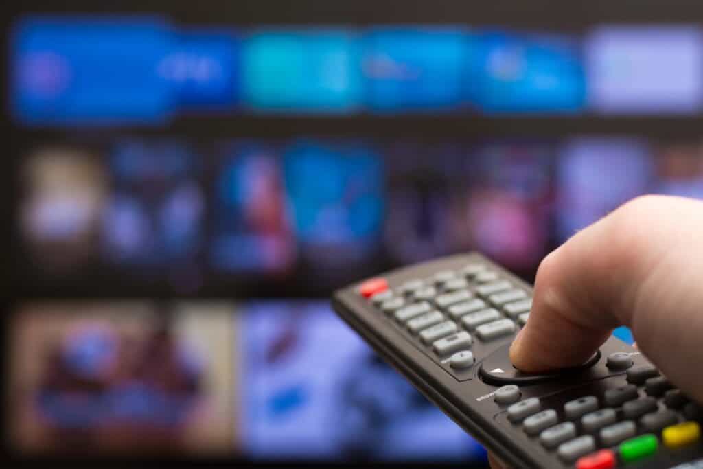 Hand holding TV remote in front of television screen for ITV soaps schedule 23rd to 27th March 2026 and spoilers