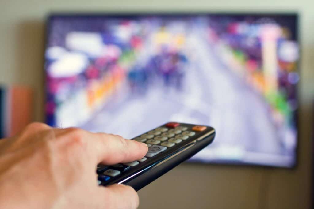 Hand holding TV remote in front of screen for ITV soaps schedule 16th to 20th March 2026 and spoilers